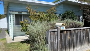 Une maison de plain-pied avec une boîte aux lettres portant le numéro « 30 », fixée à la clôture avant.