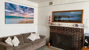 Un salon avec une cheminée, un canapé et deux tableaux.