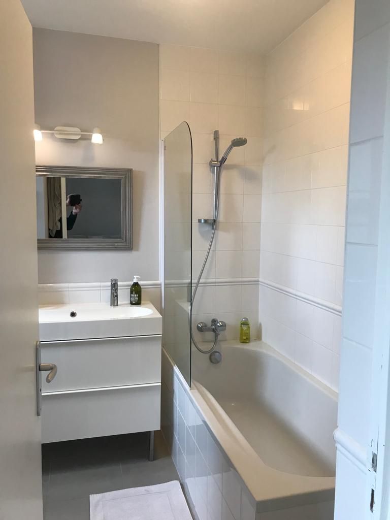 A modern bathroom with a white vanity, a large mirror, a bathtub, and a shower.