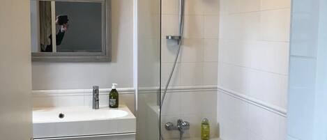 A modern bathroom with a white vanity, a large mirror, a bathtub, and a shower.