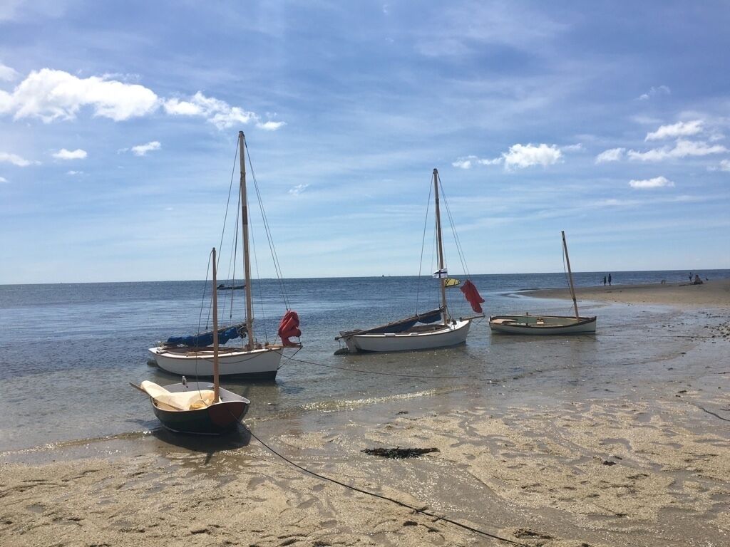 Drie boten aanmeren aan het strand, met een heldere lucht.