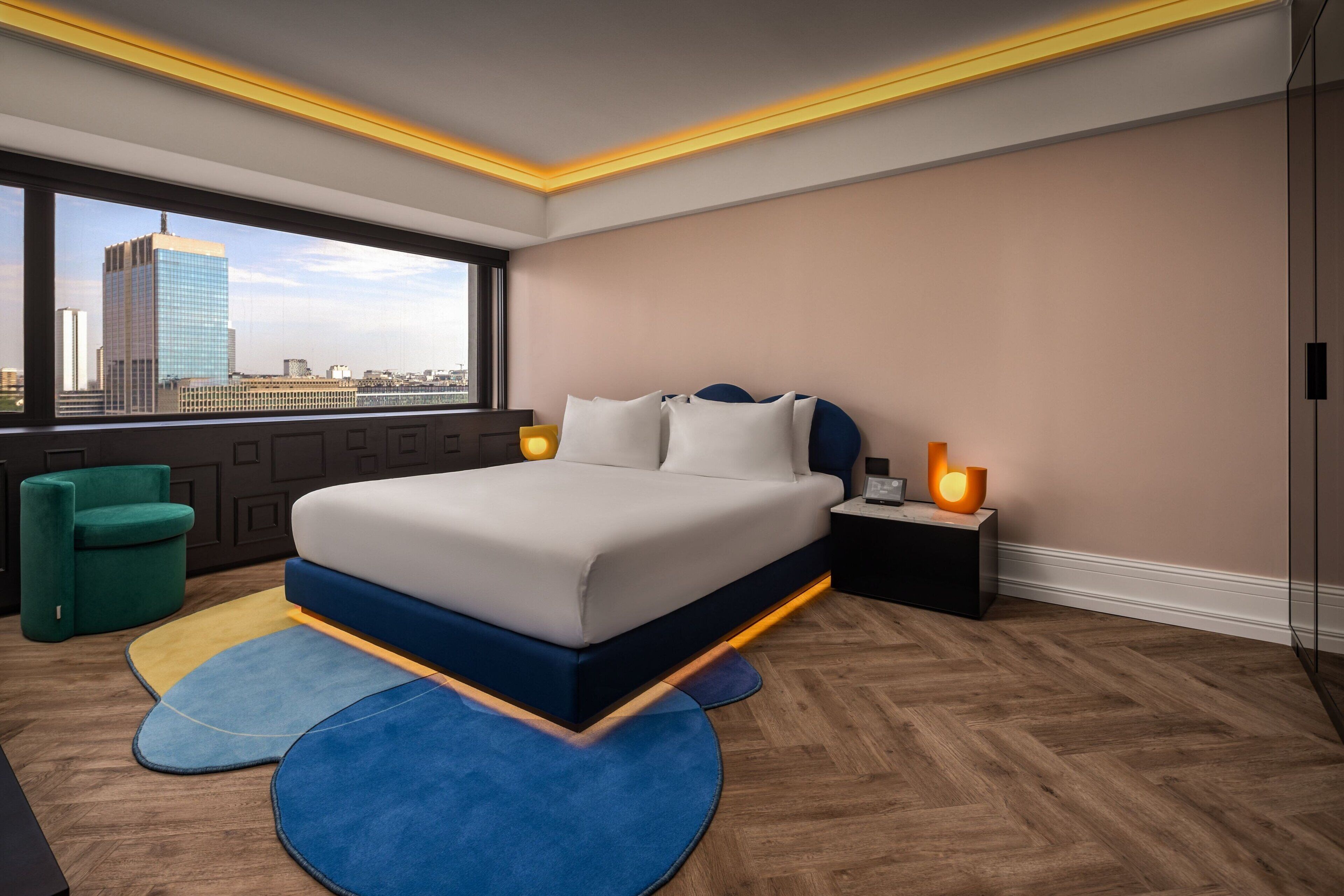 Un dormitorio moderno con una cama grande, vistas a la ciudad y una silla verde.