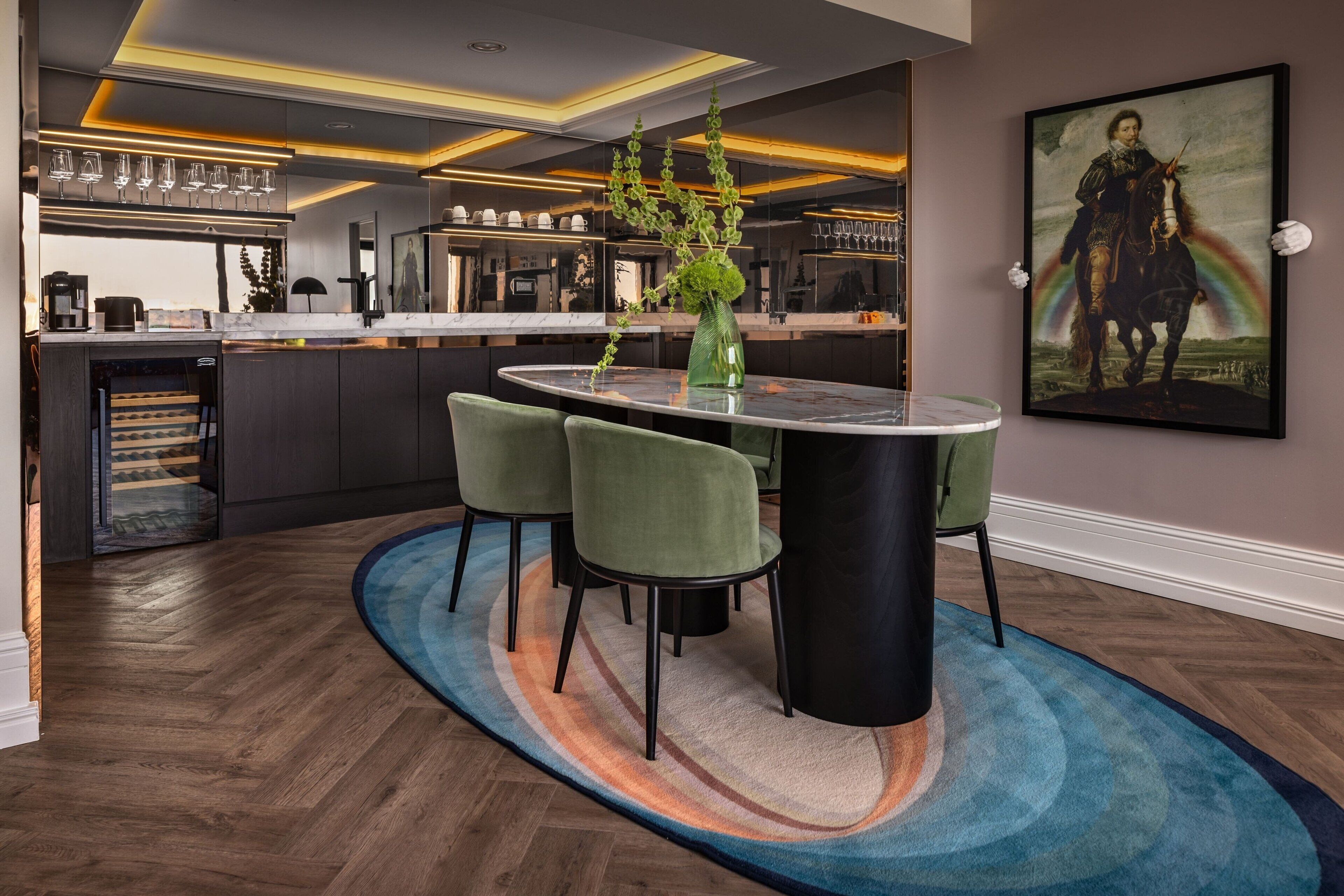 A modern kitchen with a central island, bar area, and a dining area with a round table and chairs.