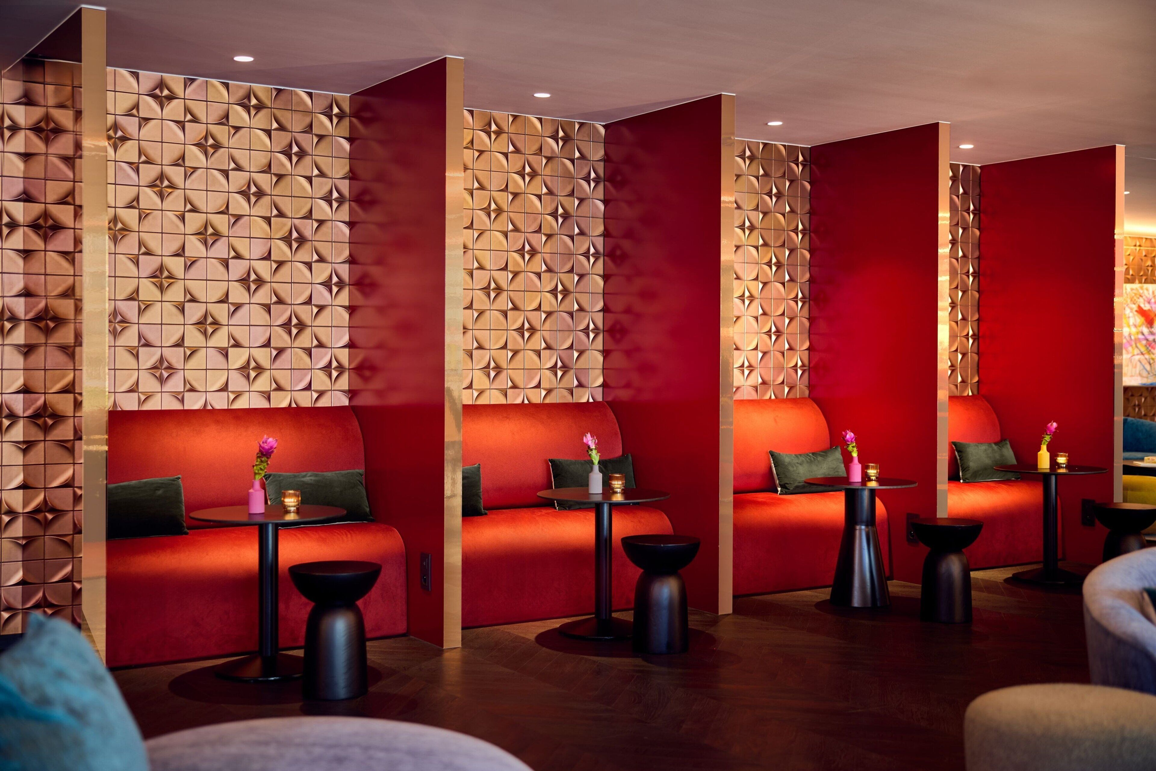 A modern lounge area with red sofas, black tables, and geometric patterned walls.
