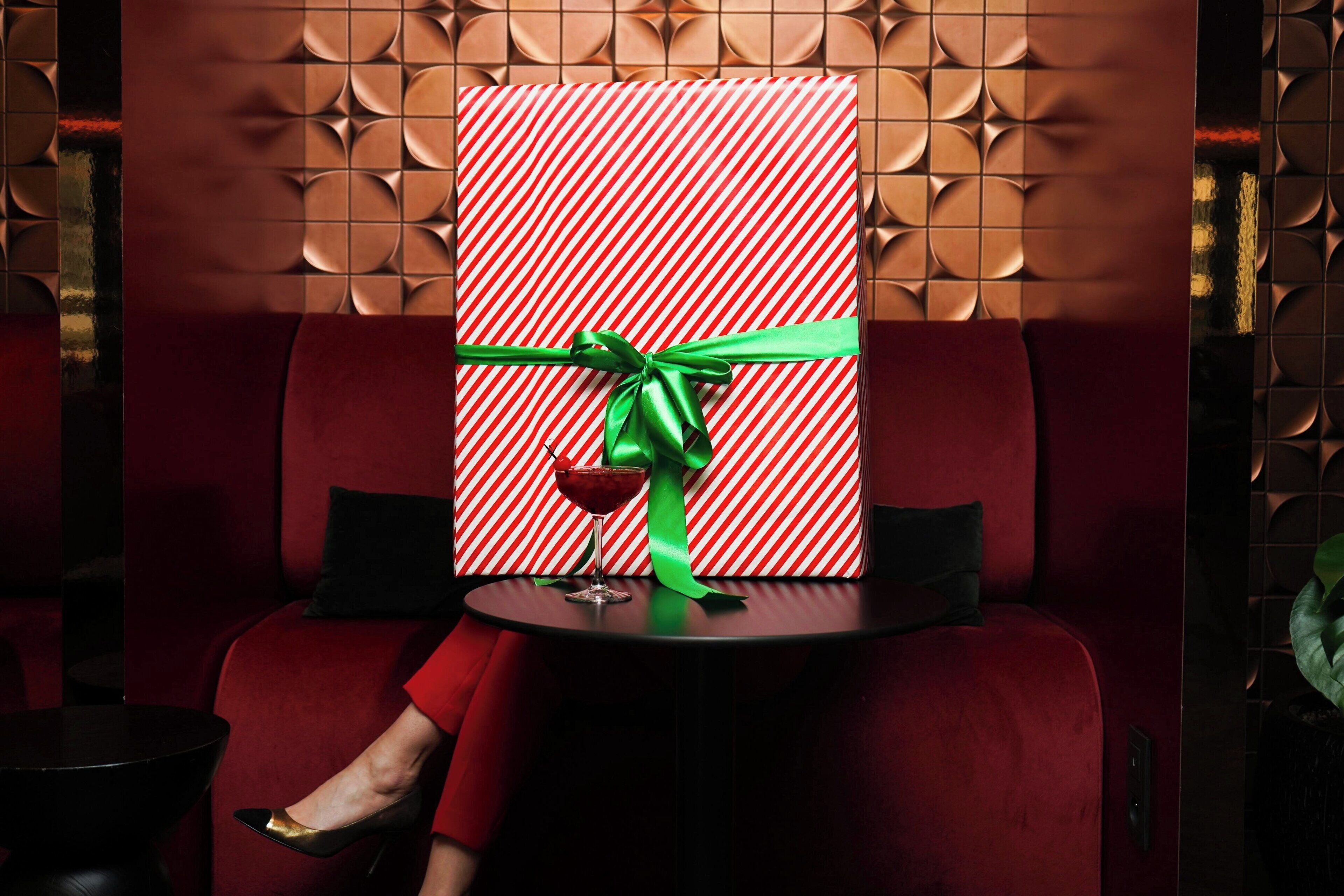 A red sofa with a patterned wall behind it.