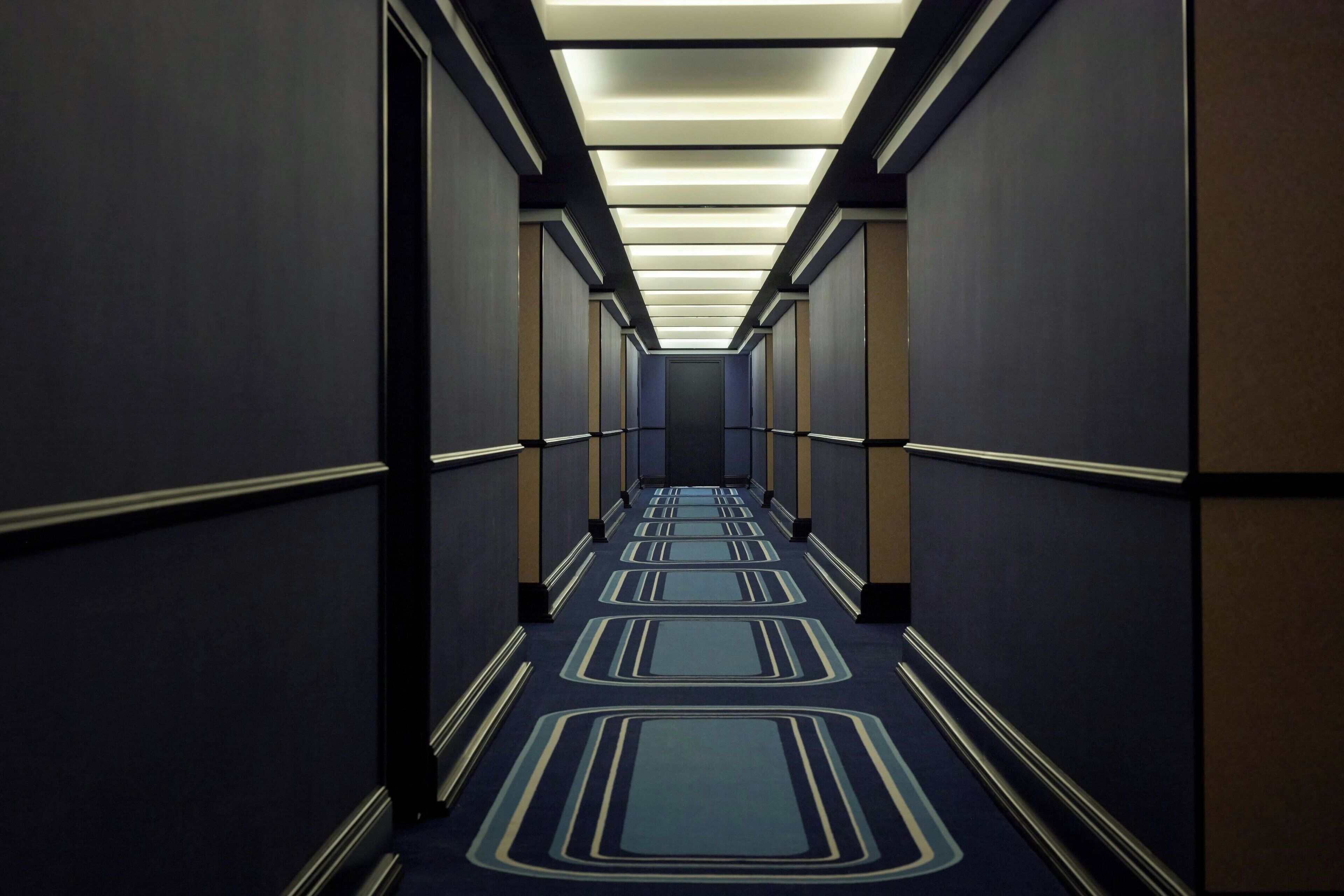 Un pasillo largo y estrecho con alfombra estampada e iluminación empotrada.