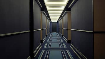 Un pasillo largo y estrecho con alfombra estampada e iluminación empotrada.