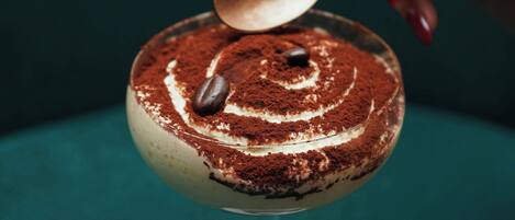 A dessert with a spoon on top, placed on a teal surface.