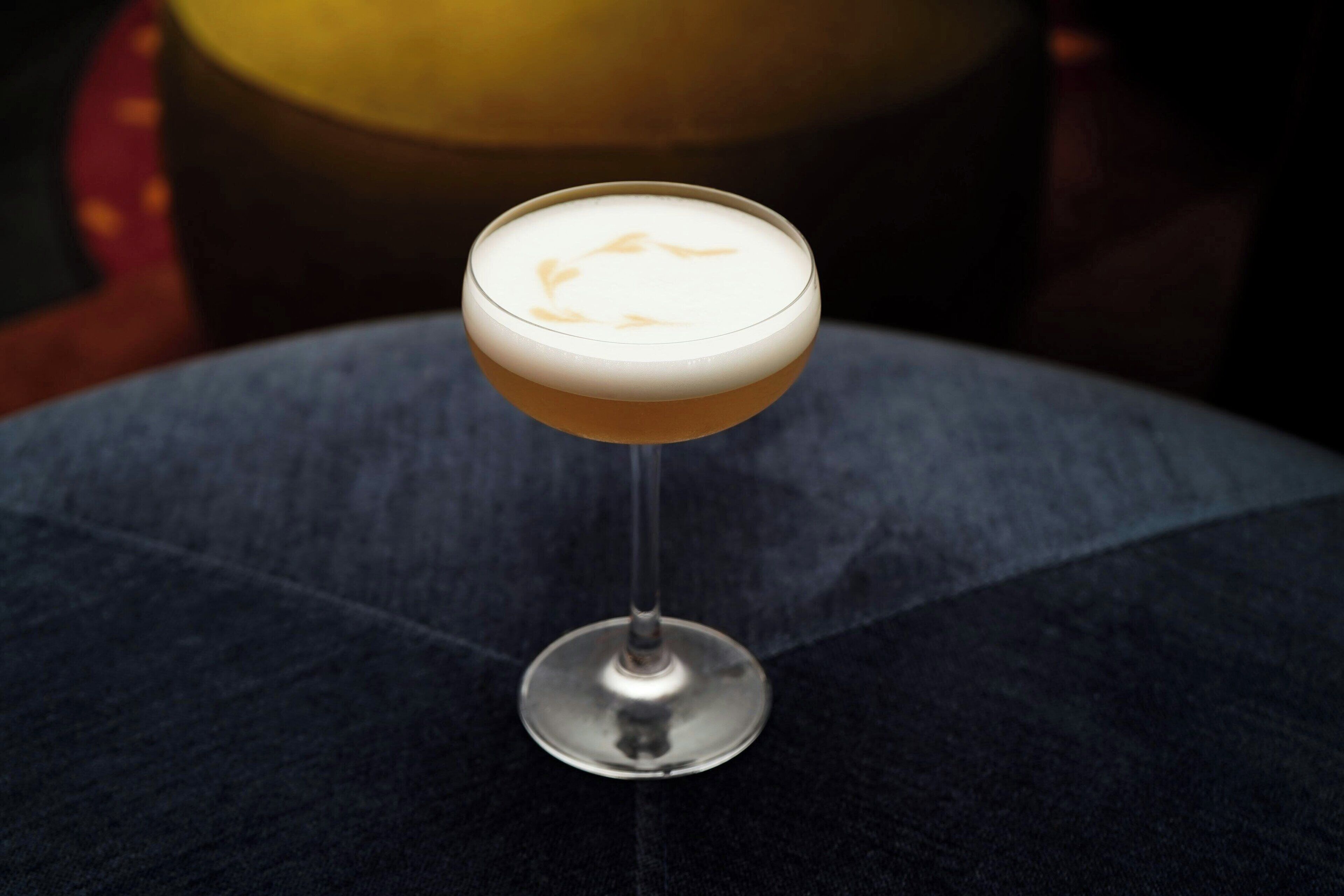 Een cocktail in een longdrinkglas op een ronde tafel.