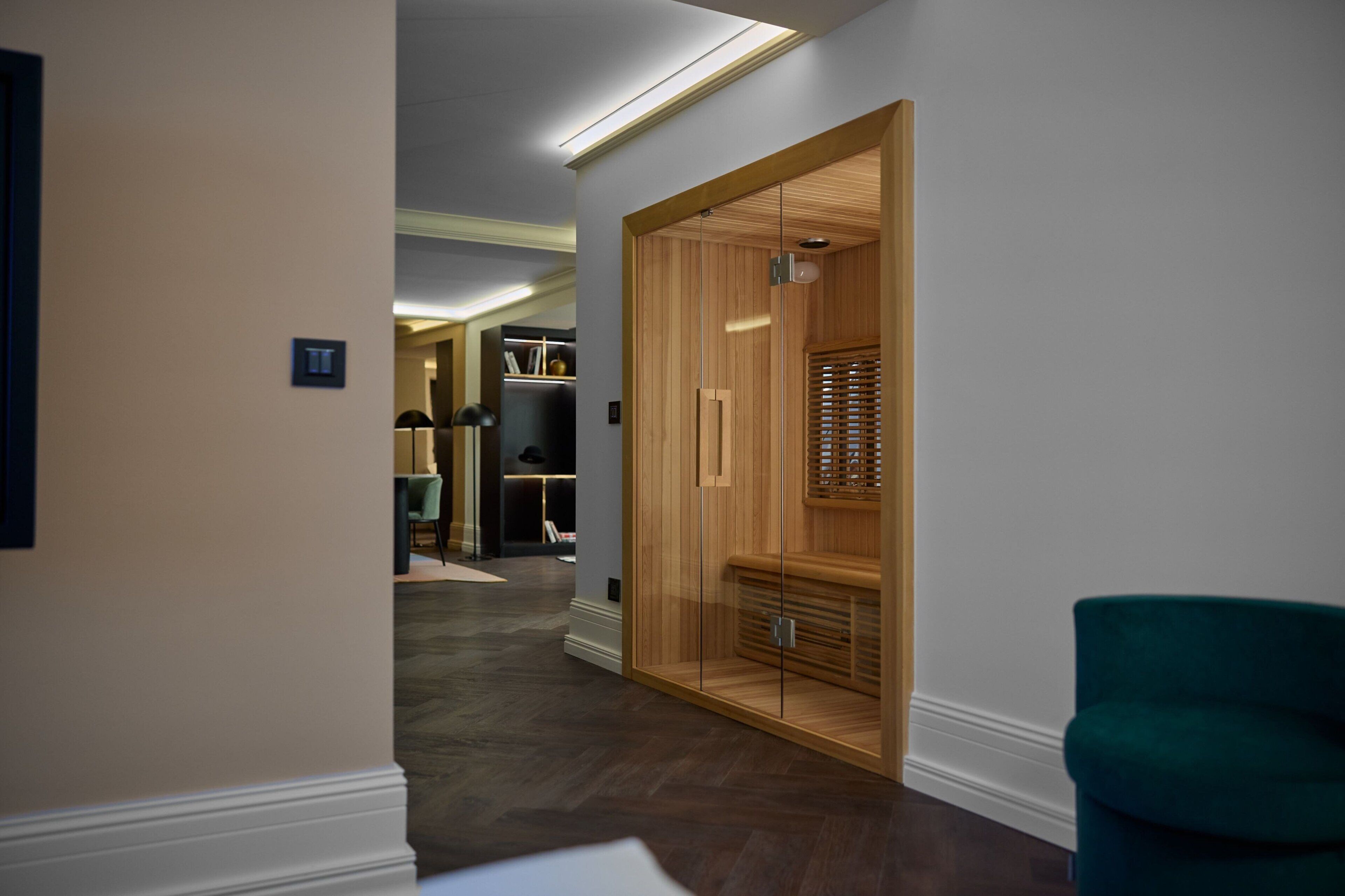 A hallway with a wooden wardrobe, a teal chair, and a modern interior design.