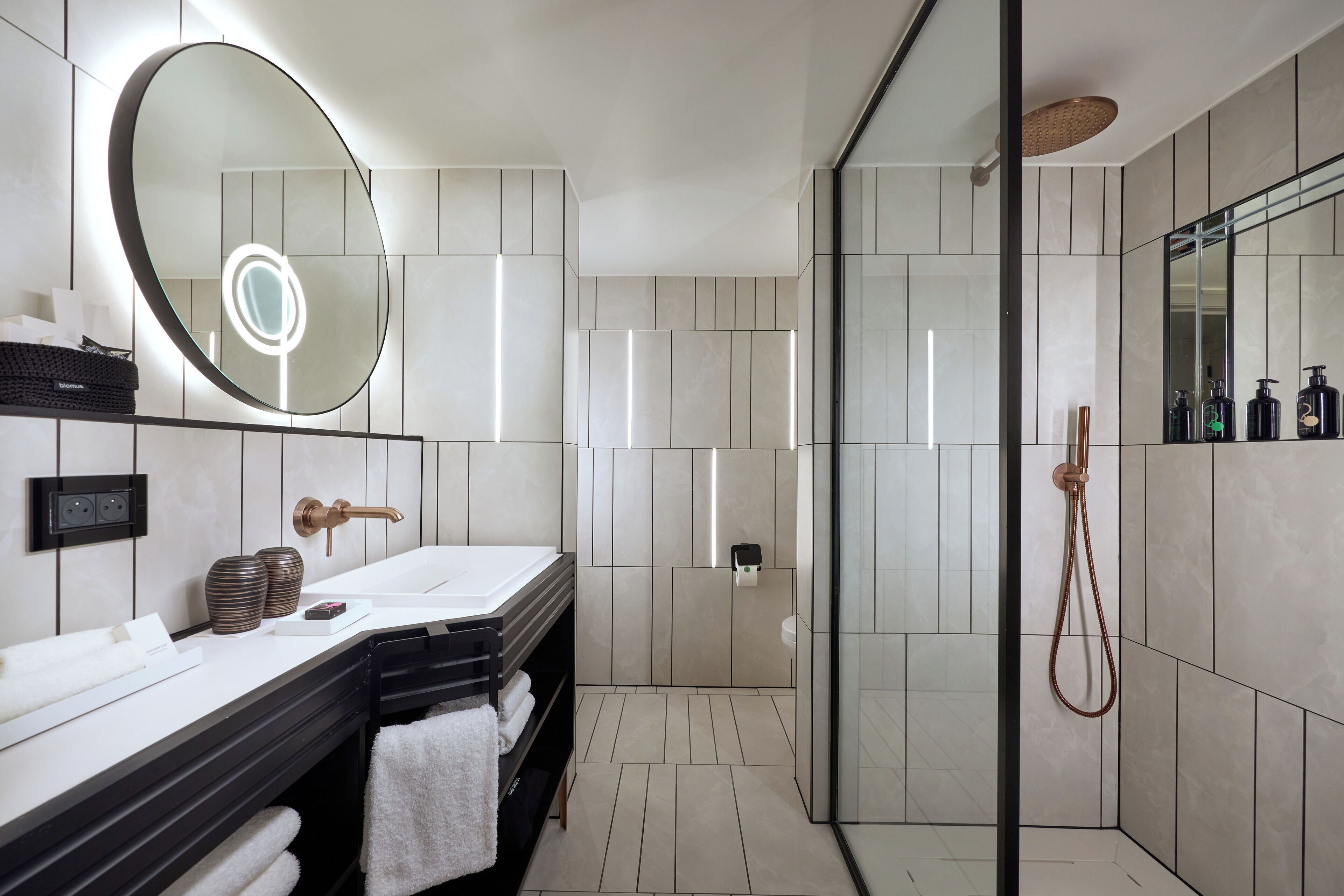 Un baño moderno con un espejo grande, lavamanos dobles, cabina de ducha de vidrio y un perchero para toallas.
