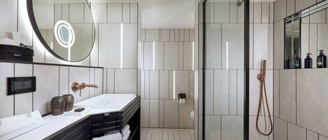 Un baño moderno con un espejo grande, lavamanos dobles, cabina de ducha de vidrio y un perchero para toallas.