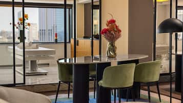 A modern dining area with a round table, green chairs, and a vase of flowers.