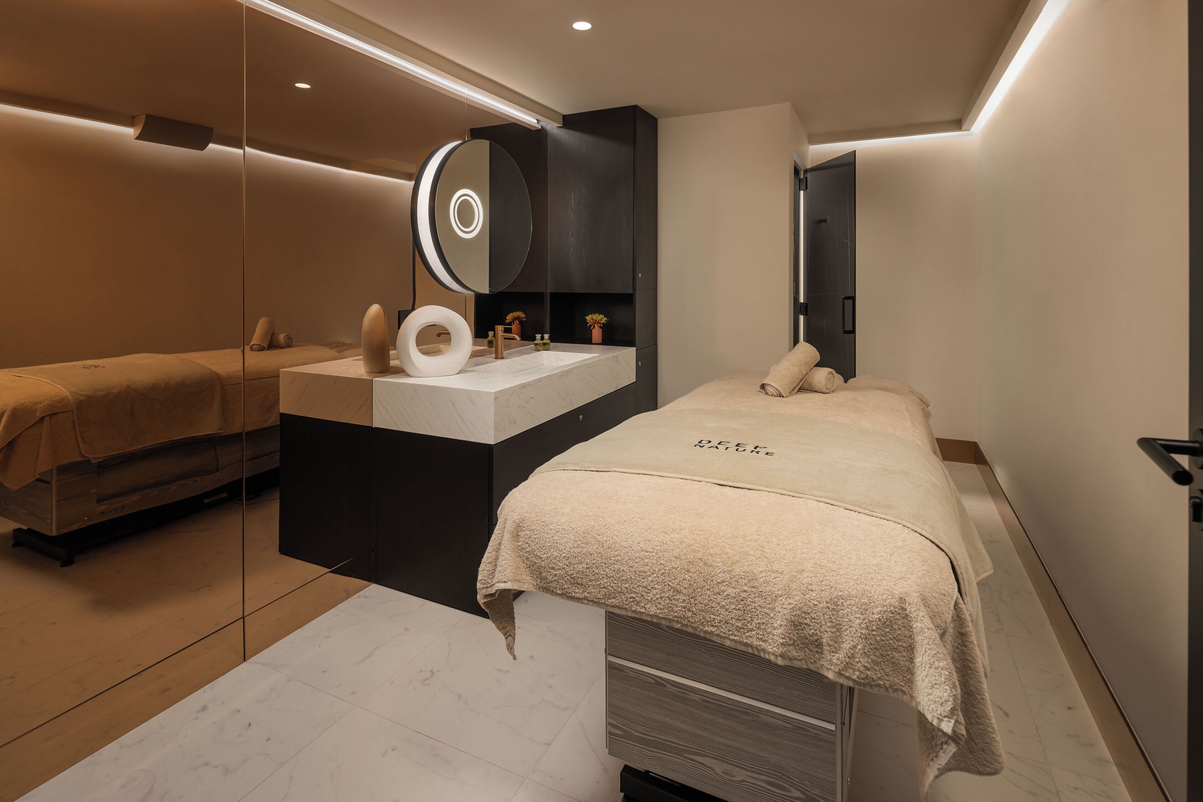 Een moderne slaapkamer met een groot bed, nachtkastje, spiegel en een ingebouwde kaptafel.