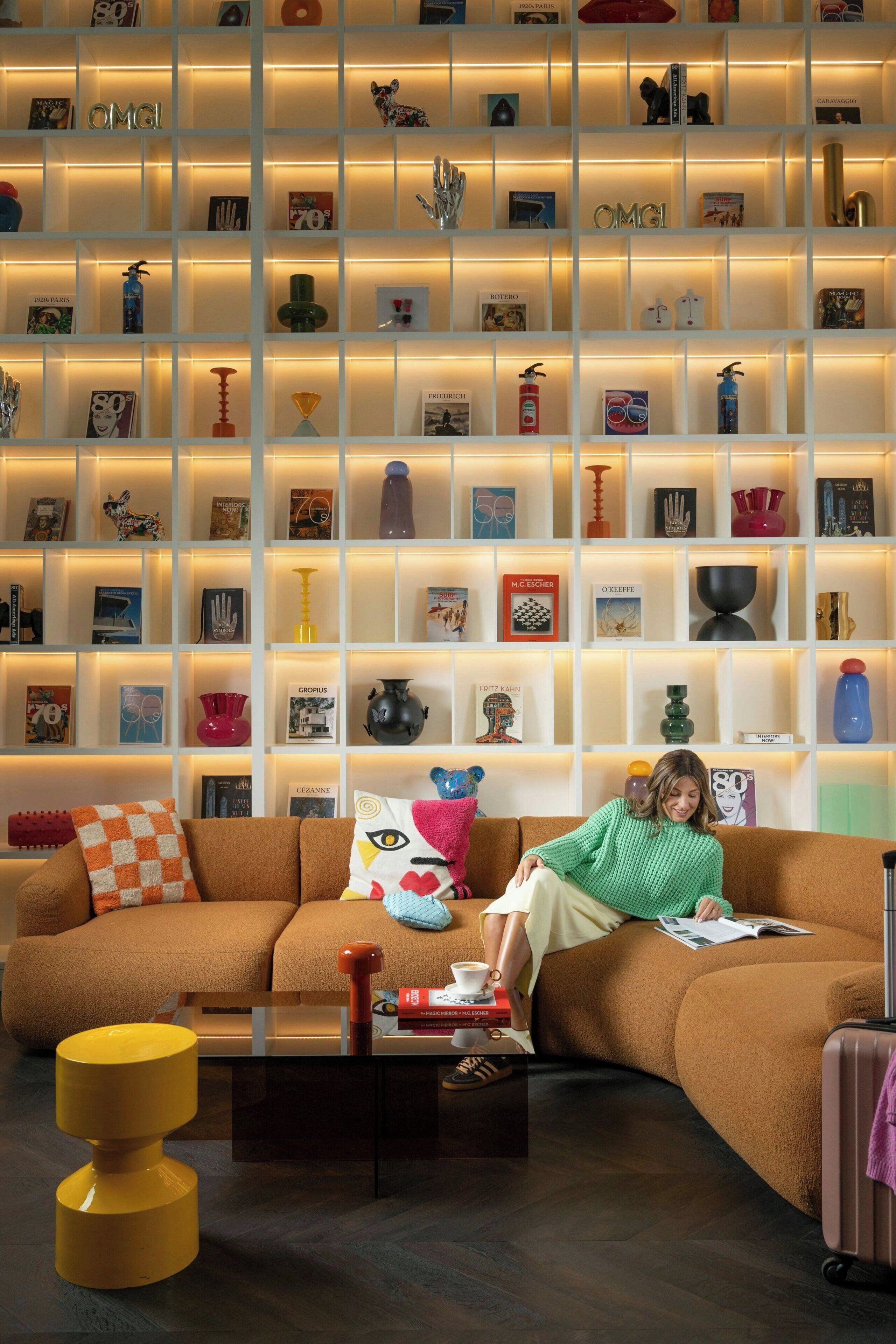 Un soggiorno moderno con un ampio divano componibile, un tavolino da caffè e una libreria piena di libri e oggetti decorativi.