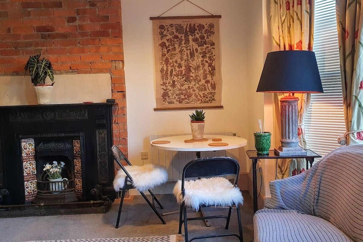 A cozy living room with a fireplace, a round table, and a sofa.