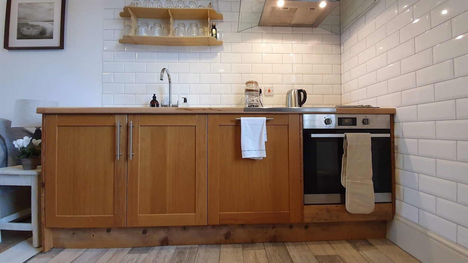 Een keuken met houten kastjes, een roestvrijstalen oven en een betegelde spatwand.