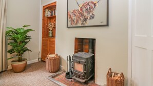 A cozy living room with a fireplace, a bookshelf, a potted plant, and a painting of a bull.