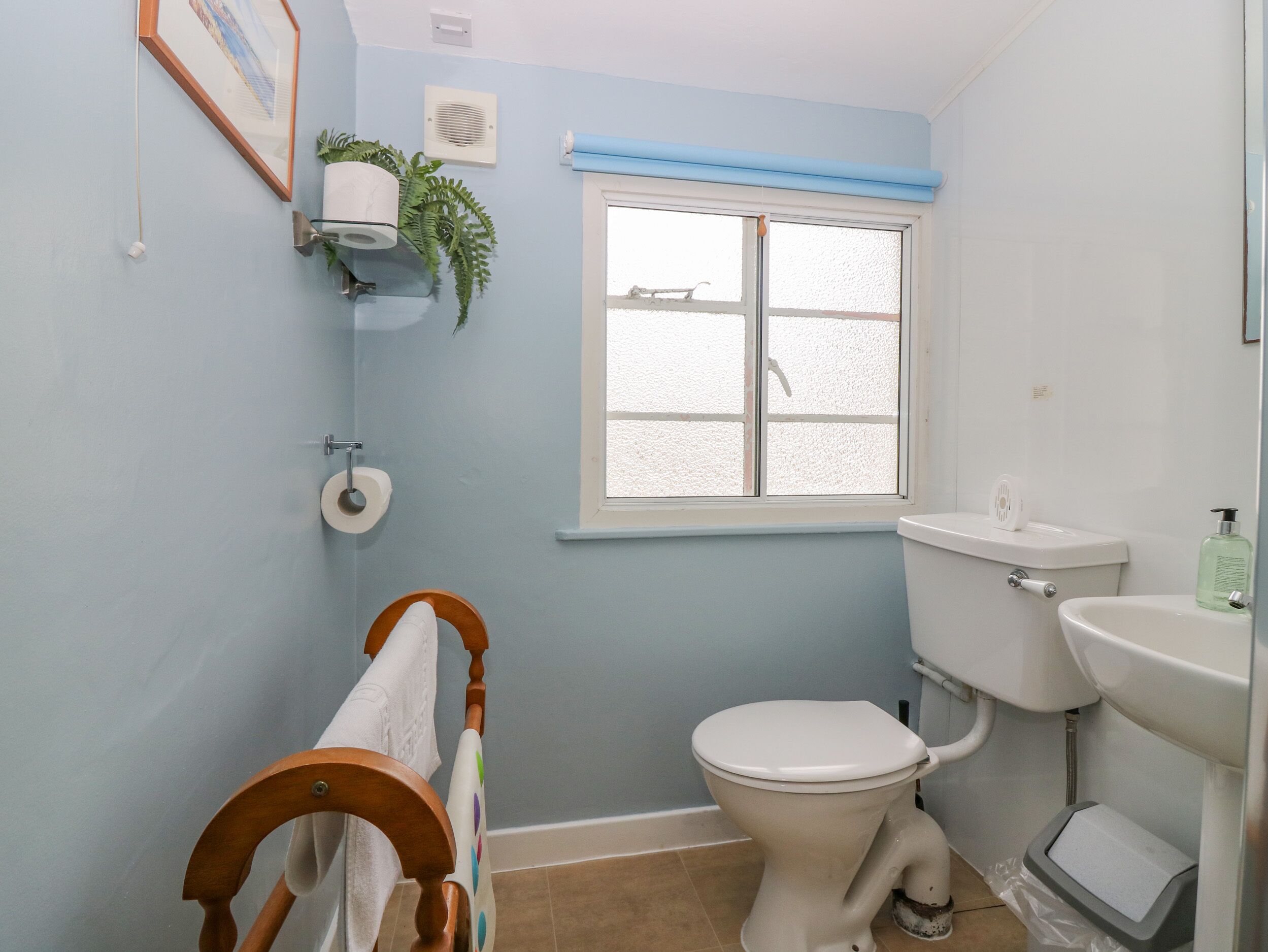 A bathroom with a toilet, sink, and window.