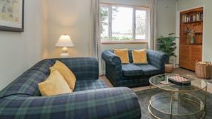 A living room with two sofas, a lamp, a window, and a bookshelf.