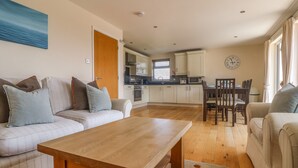 A modern living room with a sofa, a wooden coffee table, and a dining area with a table and chairs. - Redwood, Retallack (St. Columb Major)