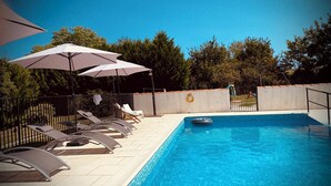 A swimming pool with lounge chairs and umbrellas, surrounded by a fence and trees. - Gîte "La Longère", Domaine Métairie des Gâcheries, Dordogne/Périgord Vert (Champagne-et-Fontaine)