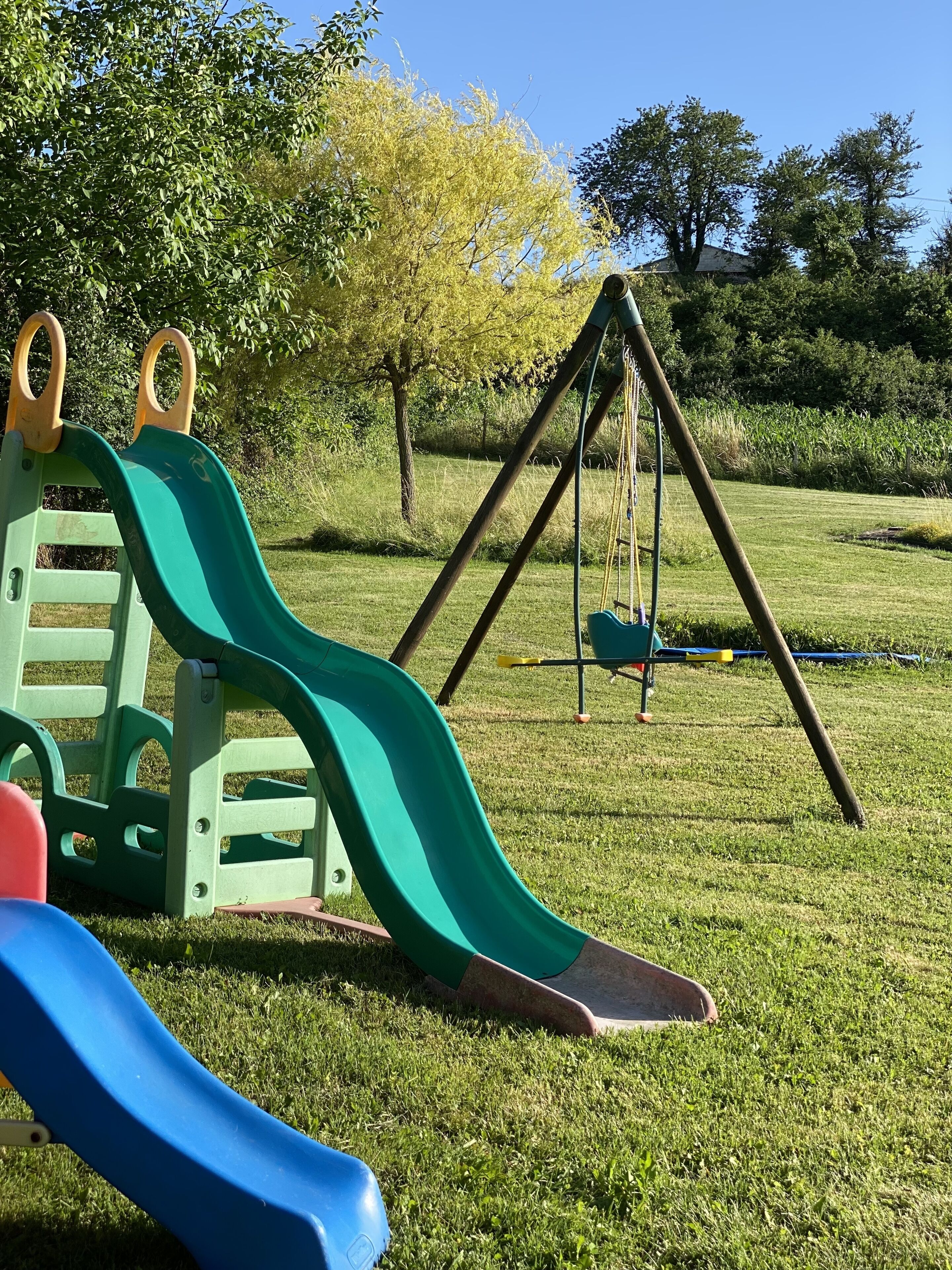 A playground with a green slide and a swing set.