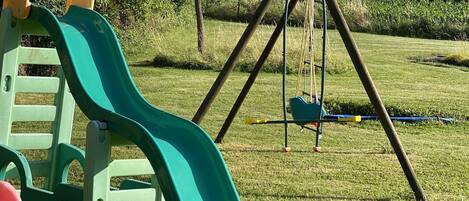 A playground with a green slide and a swing set.
