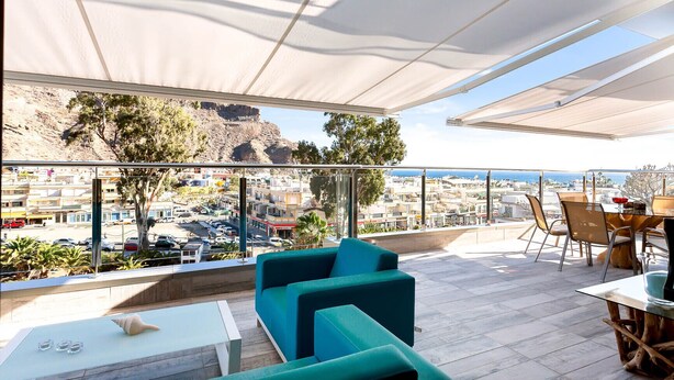 Une terrasse sur le toit offrant une vue sur le paysage urbain et les montagnes.