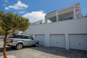 Un bâtiment moderne à deux étages, doté d’un garage et d’un arbre devant.