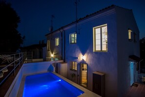 A two-story house with a swimming pool, multiple windows, and a balcony.