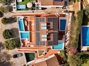 Une vue aérienne d’un hôtel doté de plusieurs piscines, d’espaces de détente en plein air et de panneaux solaires.