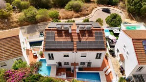 Edifici de dues plantes amb panells solars a la teulada, piscina i zona de jardí.