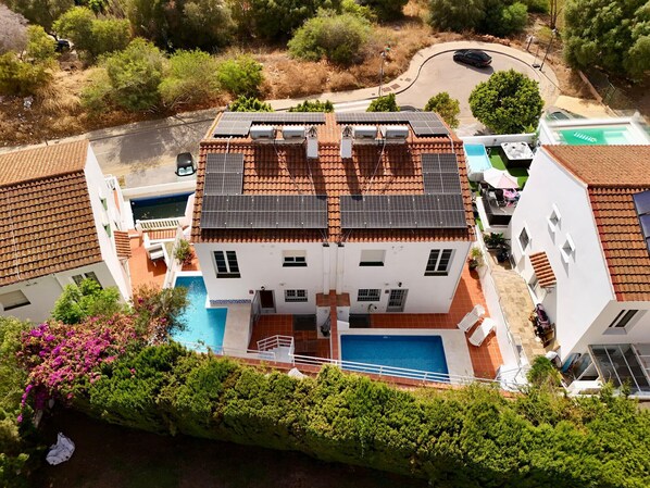 Un bâtiment à deux étages, doté de panneaux solaires sur le toit, d’une piscine et d’un espace jardin.