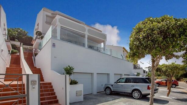 Una casa moderna de dos pisos amb una escala que condueix al pis superior, un garatge i un totveu estacionat.