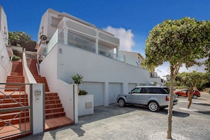 Ein modernes, zweistöckiges Haus mit einer Treppe zum Obergeschoss, einer Garage und einem abgestellten Geländewagen.