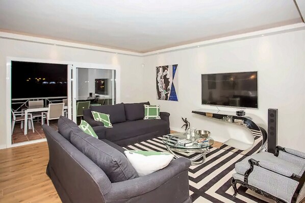 A modern living room with a sofa, armchairs, a coffee table, and a TV.