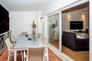 Un salon moderne avec une porte vitrée donnant sur un balcon, un téléviseur à écran plat et un canapé.