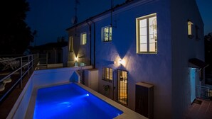 Une maison à deux étages avec une piscine, de nombreuses fenêtres et un balcon.
