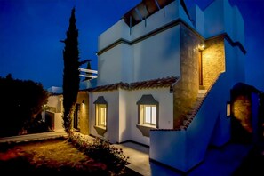 Ein modernes, zweistöckiges Gebäude mit Innenhof, das eine Treppe mit einem markanten Design und beleuchtete Fenster zeigt.