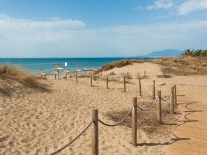Una playa arenosa con pasarelas de madera y barreras de cuerda.