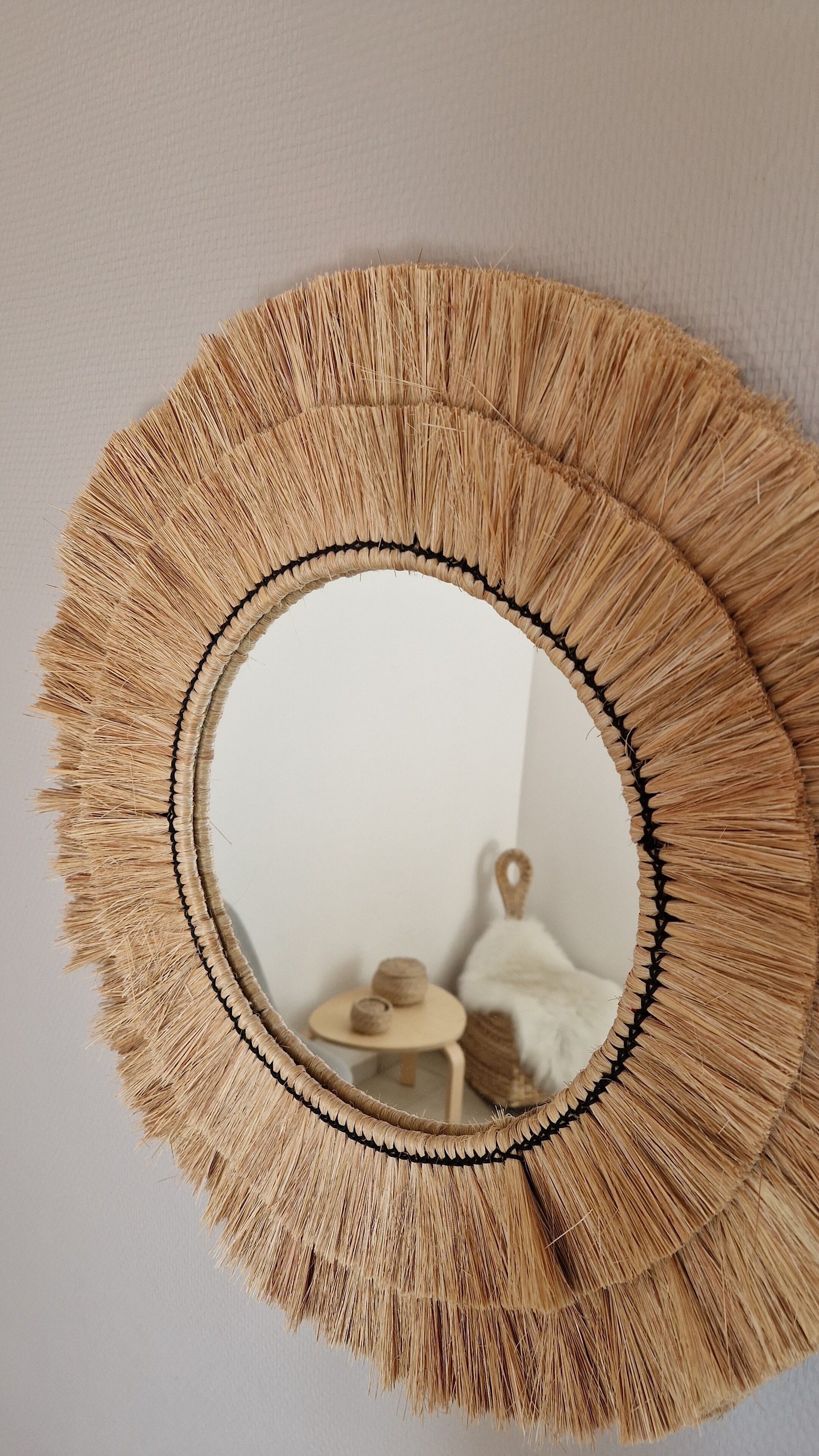 A round mirror with a fringe design.