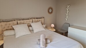 A neatly made bed with a headboard, a bedside lamp, a chair, and a small table.