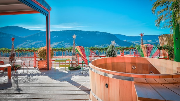 A wooden deck with a hot tub, colorful chairs, and star-shaped decorations against a mountainous backdrop.
