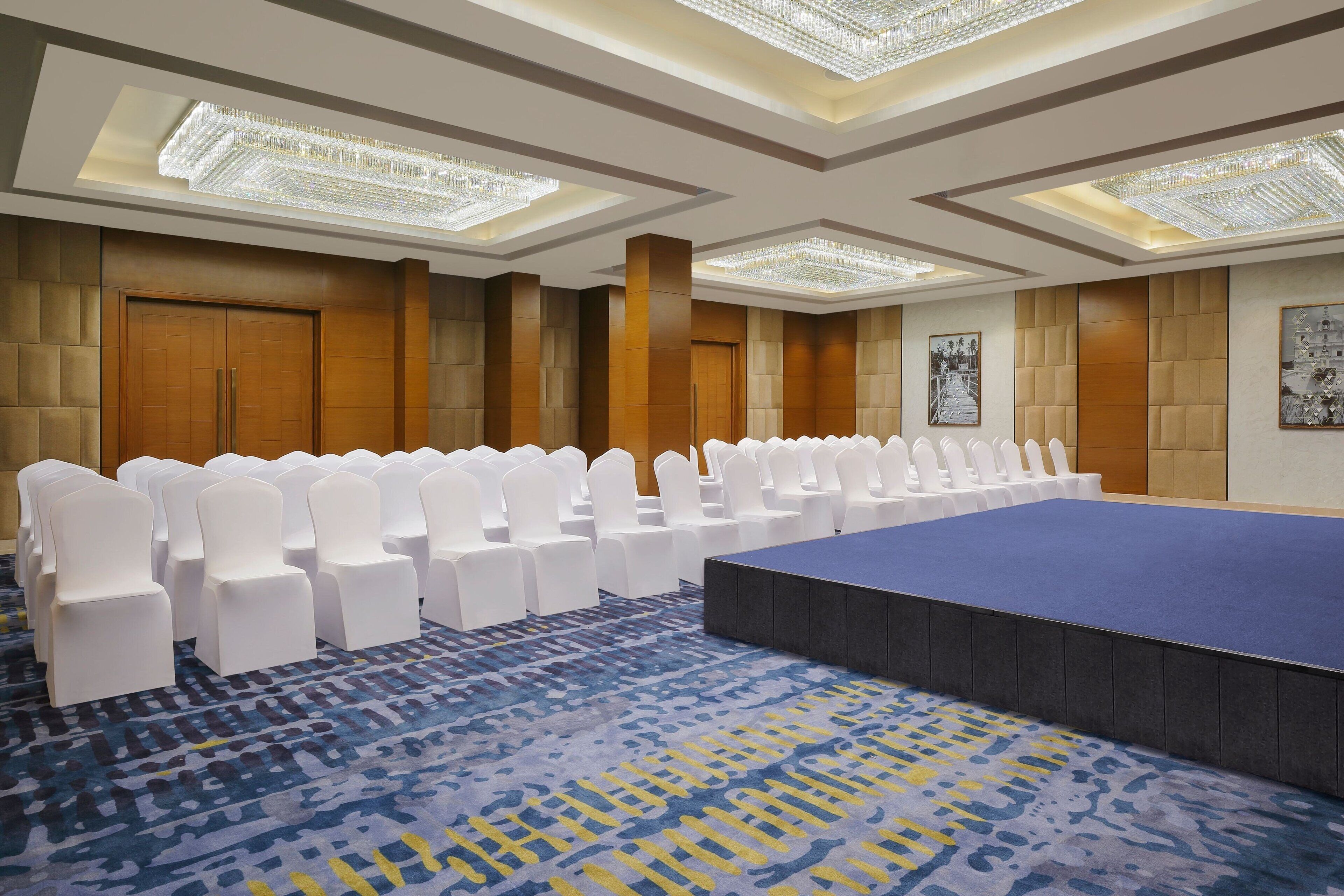 A conference room with a long table, white chairs, and a patterned carpet.