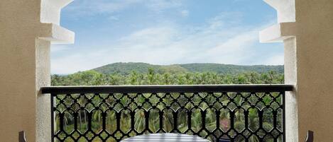 A balcony with a view of green hills and a clear sky.