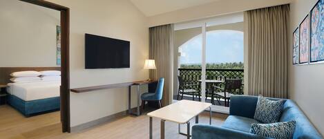 A hotel room with a bed, a desk, a sofa, and a balcony with a table and chairs.
