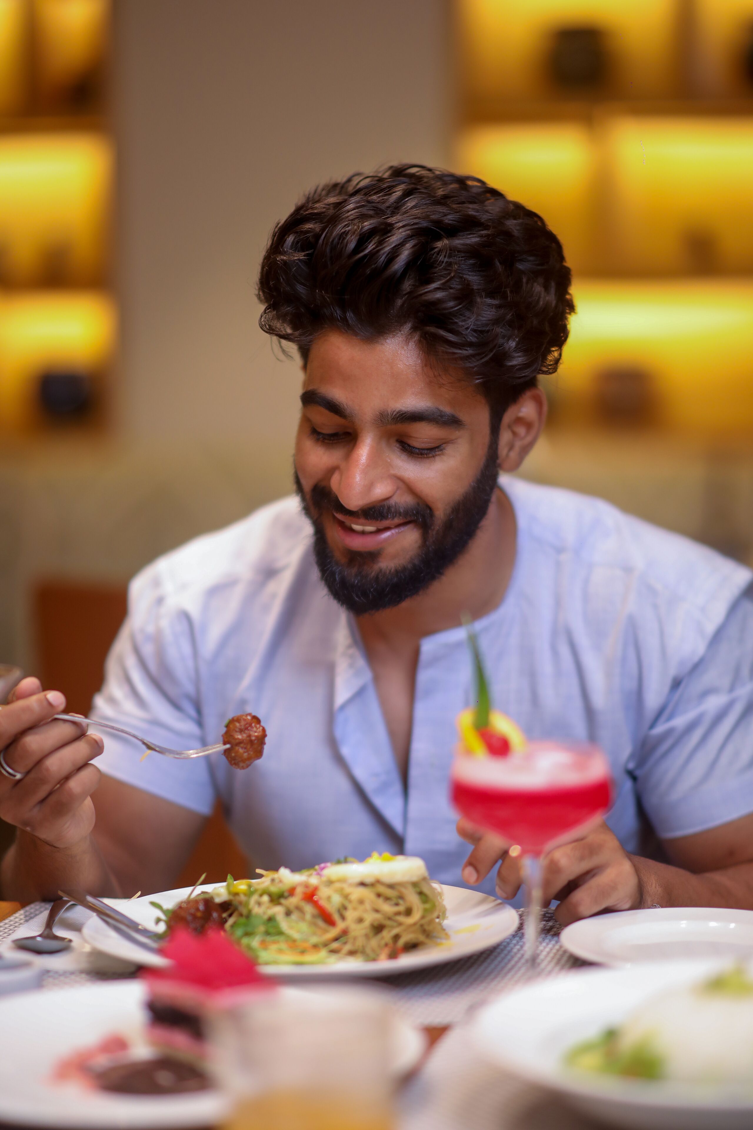 A person dining at a table with a variety of dishes and a cocktail.
