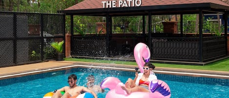 Un área de piscina con un espacio de descanso techado, identificado como