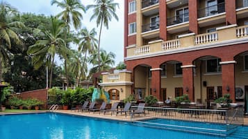 Een buitenzwembad, ligstoelen bij het zwembad